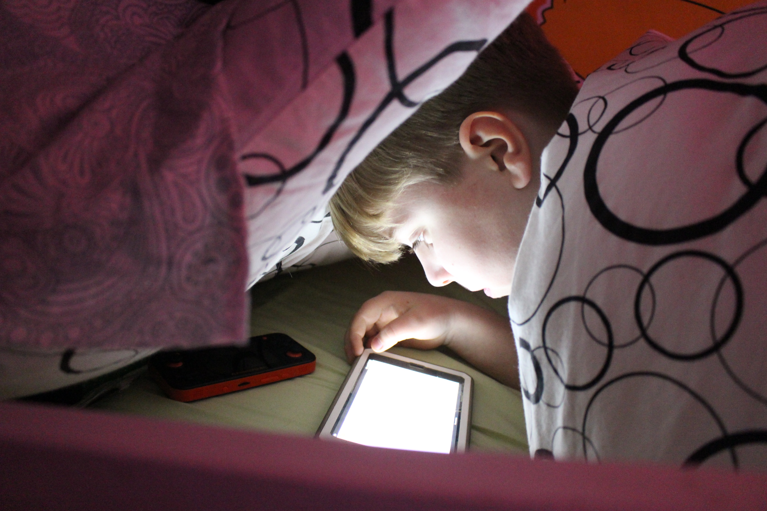 Photo of a child using a tablet at night